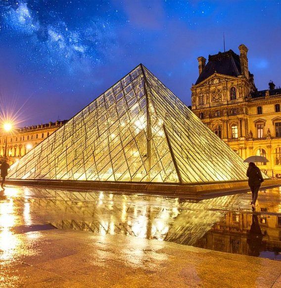 The glass pyramid of the Louvre lit up at dusk in Paris